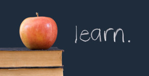 "learn" written on blackboard with apple, books